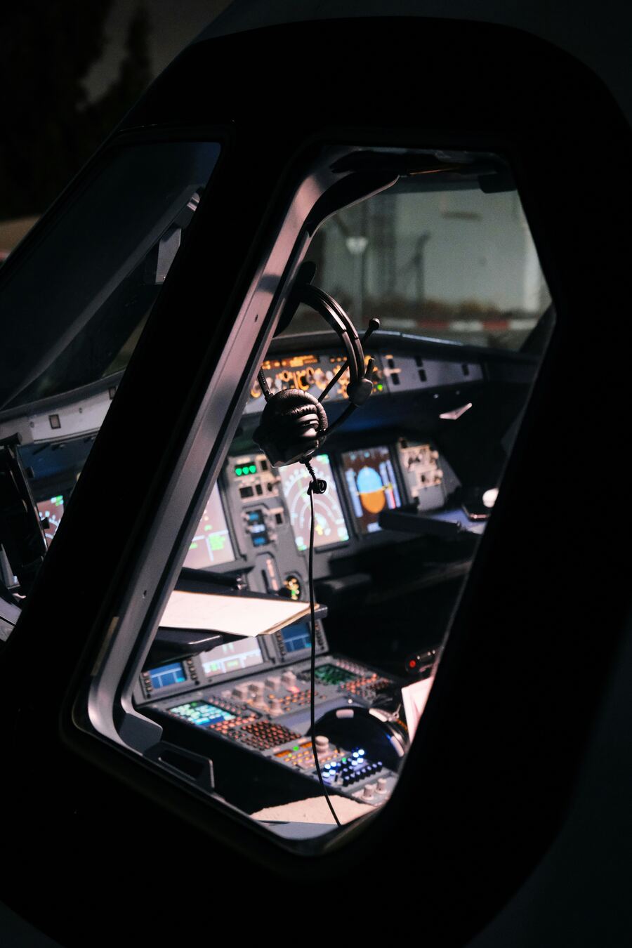 Airline flight deck at night seen through the cockpit window, headset hanging above the glareshield